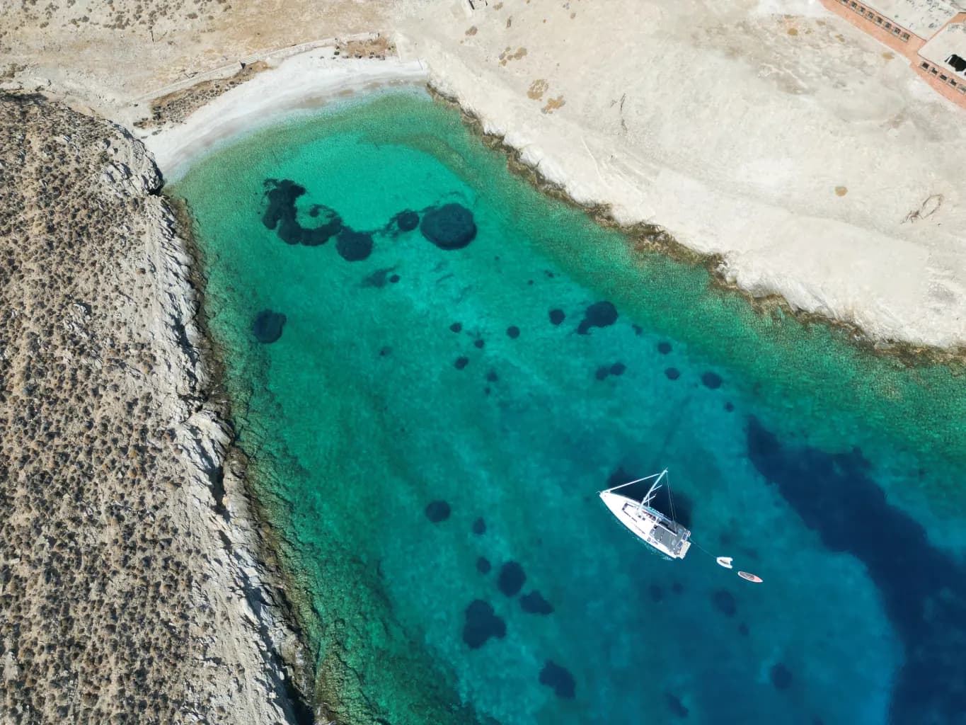 Drone view of a yacht anchored in a turquoise cove