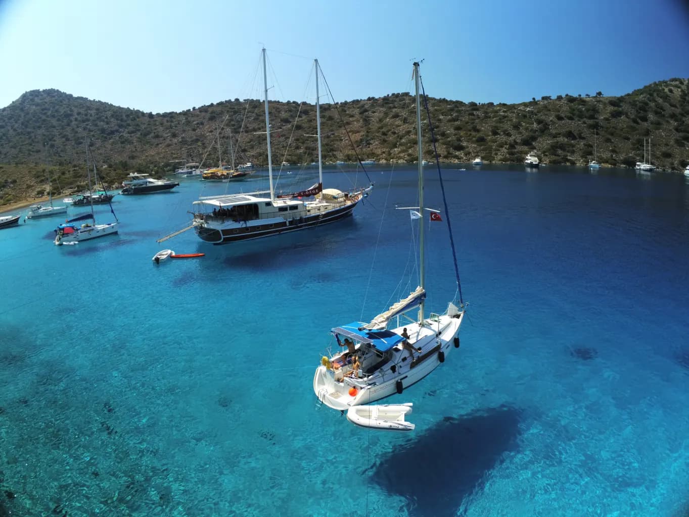 Boats swinging at anchor over clear shallow water
